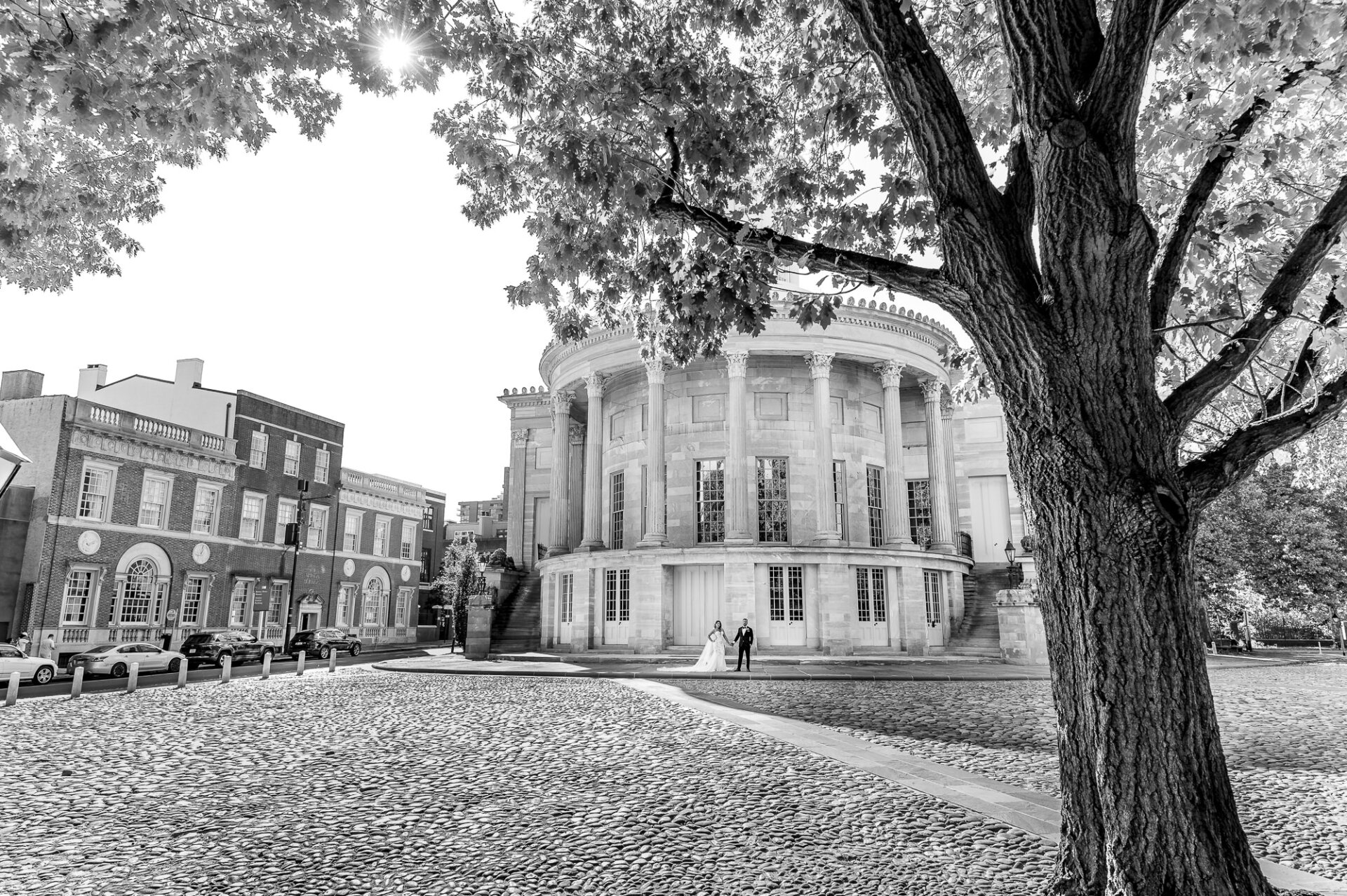 Wide black and white photo of newlyweds standing outside historic Merchants' Exchange Building